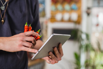 close up of man holding digital tablet and red hot paprika