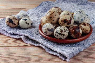 Top view of Quail eggs in wooden plate on wooden background. Selective focus.