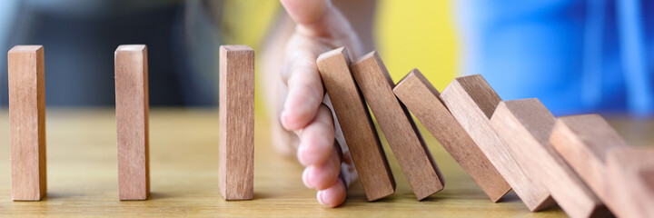 Business woman protects wooden block from falling planning and strategy