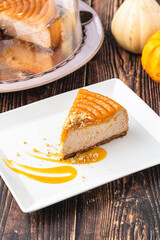 Delicious pumpkin cheesecake in white plate on wooden table