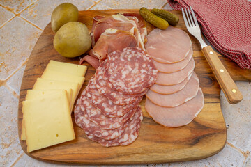 tranches de fromage à raclette et charcuterie sur une planche à découper