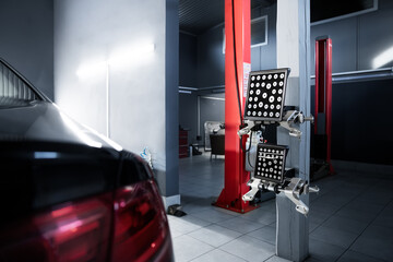 Black modern car indoors service maintenance repair center against 3d laser sensor equipment for diagnostics and wheel alignment. Vehicle inside garage workshop auto camber toe check and fixing work