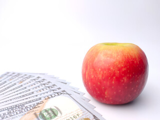 Banknotes and red apple on a white background with copy space.