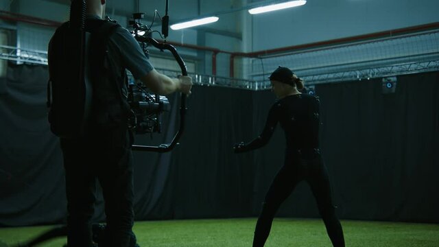 Cameraman filming actors performing some fight moves wearing motion capture suits as a game characters. Motion capture is an unparalleled method for making animated characters move more realistically