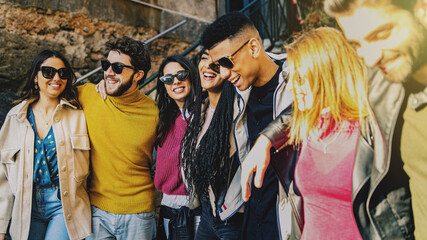 Young multicultural people having fun time together hugging in the street