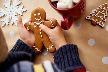 Christmas homemade gingerbread cookies in child hands among festive Christmas decorations with hot...