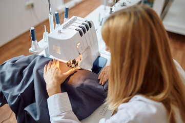 Dressmaker works on sewing machine at workplace