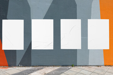 Modern urban street scene with colorful geometrical wall and four white glued wrinkled poster...