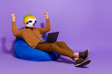 Full body portrait of crazy delighted sloth head person sit blue bag raise fists isolated on violet...
