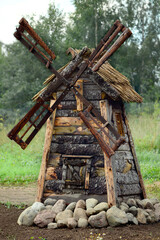 Real high wooden old windmill with spinning blades and stones on a country plot. Rustic theme as a decoration.