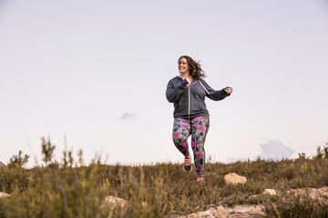 Plus-Size-Model jogging in the countryside at sunset