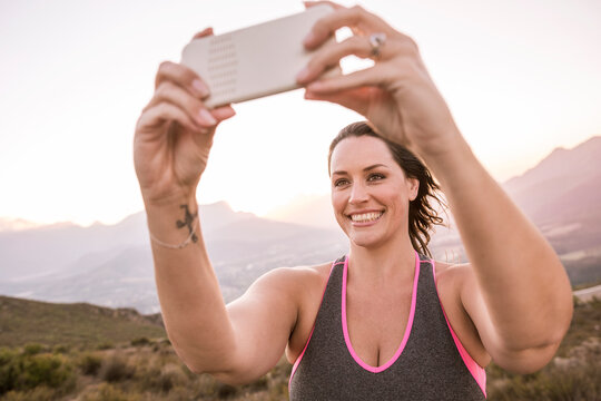 Plus-Size-Model taking smartphone photo in the countryside at sunset