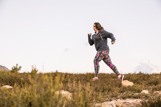 Plus-Size-Model jogging in the countryside at sunset