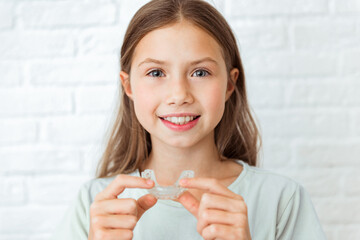 Smiling child girl with perfect and healthy teeth using removable braces or aligner for straightening and whitening teeth. Orthodontic treatment for correction of bite - obrazy, fototapety, plakaty