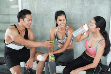 Smiling group of asia friends, happy young women and men relax together after a workout at gym...
