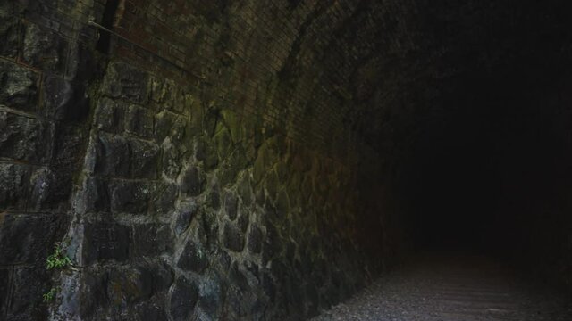 Stone walls of dark abandoned tunnel along Abandoned Fukuchiyama Railway