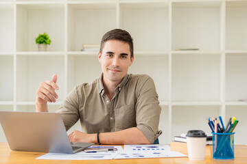 young businessman looking at market research report Analyze statistical data in charts. Develop a growth strategy Work on a computer alone in a modern office