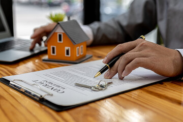 A salesperson of a housing project is drafting a sales contract for a customer who reserves a house in the project he manages. Real estate trading concept.