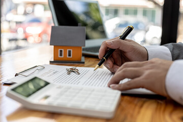 Fototapeta premium Man checking documents on table, housing salesman checking for correctness of contract documents before bringing customers to sign the deal. Real estate trading concept.