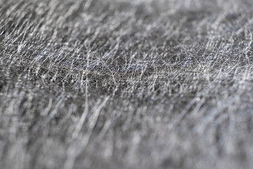 Textured background from interlacing of thin silver threads. Close-up of silver felt. Shallow depth of field