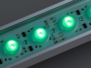 Green LED flood light in aluminum housing with wire on dark background