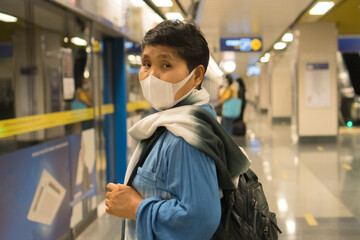 Asian traveler senior woman wearing face mask at gate metro or subway train looking camera while...