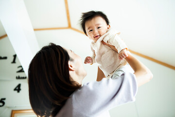母親に抱き上げられて笑顔の赤ちゃん