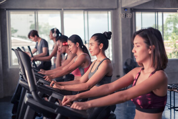 Fototapeta premium group friends working out on exercise bike and wearing sportswear in fitness or gym center, strength sporty and weight loss concept