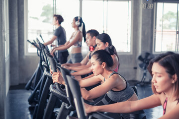 group friends working out on exercise bike and wearing sportswear in fitness or gym center,...