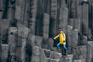 Female traveler walking on rocky formations at Reynisfjara Beach, Vik, Iceland