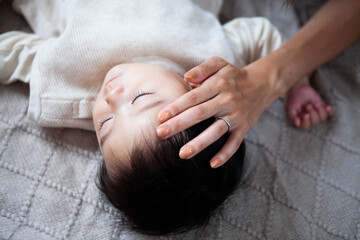 昼寝をする赤ちゃんを撫でる母親の手
