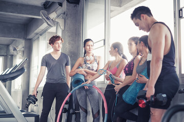 Fototapeta na wymiar Smiling group of asia friends, happy young women and men relax together after a workout at gym center, Strength sporty and weight loss concept