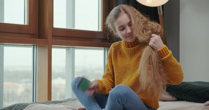 Teenager girl caring her hair in the badroom near window