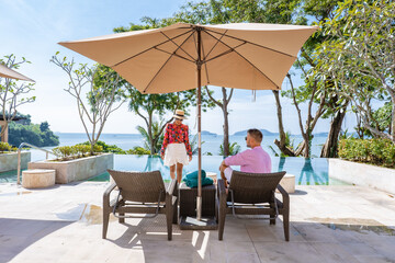 couple man and woman mid age at a luxury beach chair, on a luxury vacation in Thailand, men and...