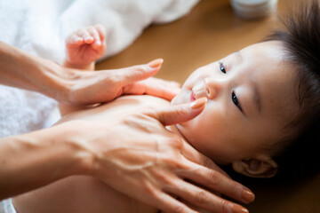 赤ちゃんの肌に保湿クリームを塗る母親