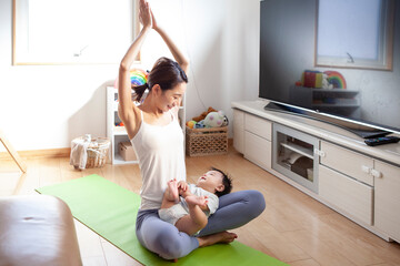 赤ちゃんと一緒にヨガをする若い母親