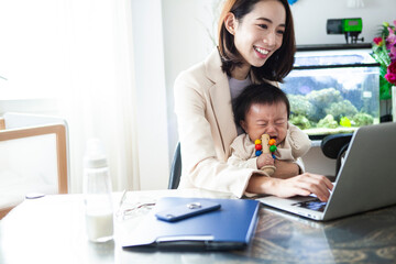 育児と仕事の両立　赤ちゃんをあやしながら在宅ワークをする女性