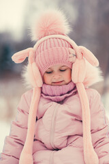 Close-up winter portrait of a happy girl in pink warm clothes