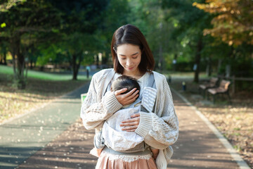 公園の歩道で赤ちゃんを抱っこするお母さん