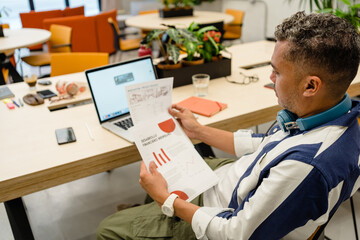 Man reading documents near laptop