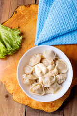 Dumplings in a white plate with salad on a wooden background.
