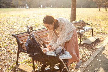 夕暮れの公園・ベビーカーに乗った赤ちゃんとお母さん - obrazy, fototapety, plakaty