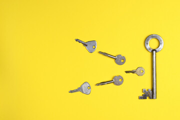 Door keys of different shapes on a bright yellow background. Trendy flat lay concept.