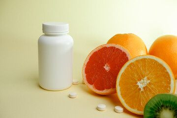 Vitamins. Medical concept. Pharmacy or natural. White bottle with vitamins, scattered pills. Juicy ripe citrus fruit slices. lemon. Orange. Grapefruit. Kiwi.