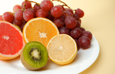 Healthy natural food. Vitamin plate. Sliced citrus fruits, orange, lemon, kiwi, grapes on a white plate.