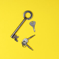 Old door keys of different shapes on a bright yellow background.