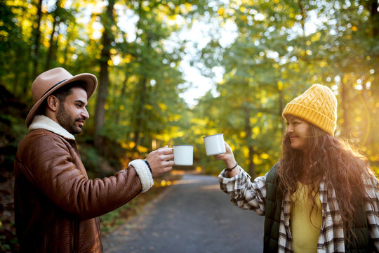 Positive couple clinking mugs in nature