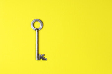 Metallic key isolated on yellow background. Flat lay.