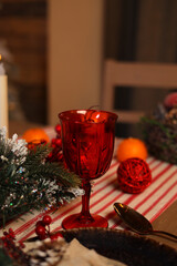 Festive decoration of the New Year's table, serving dishes for New Year's dinner, cones, tangerines, fir branches, garlands, candles and glasses, bokeh on the background. The concept of Christmas