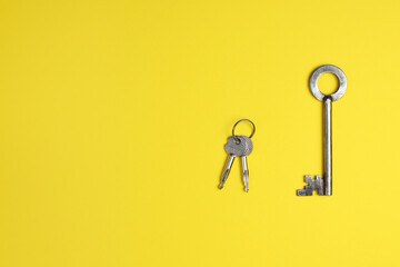 Old metallic keys isolated on yellow background. Flat lay.